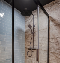 Moderne douche met zwarte regendouche en handdouche, gecombineerd met lichtblauwe glanzende tegels en beige marmerlook wand.