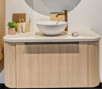 Luxe badkamermeubel met ronde witte waskom, goudkleurige kraan en beige houten fronten met verticale nerf.